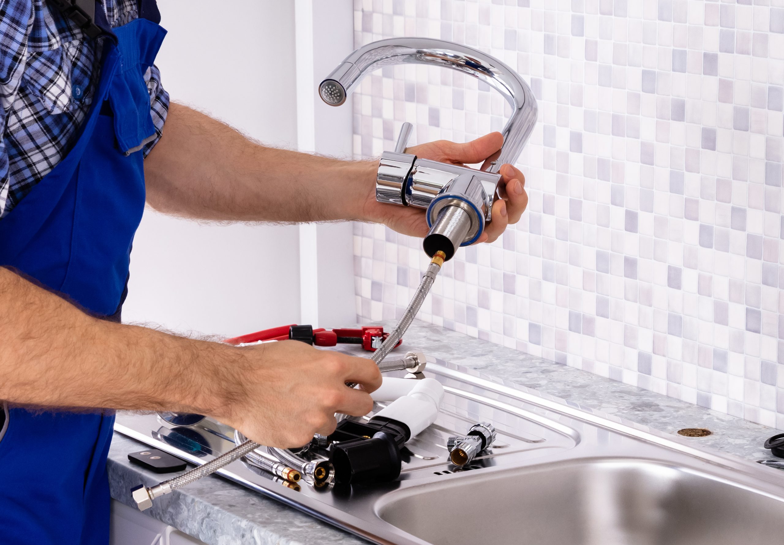 Mid Section Of Male Plumber Assembling The Kitchen Sink Faucet